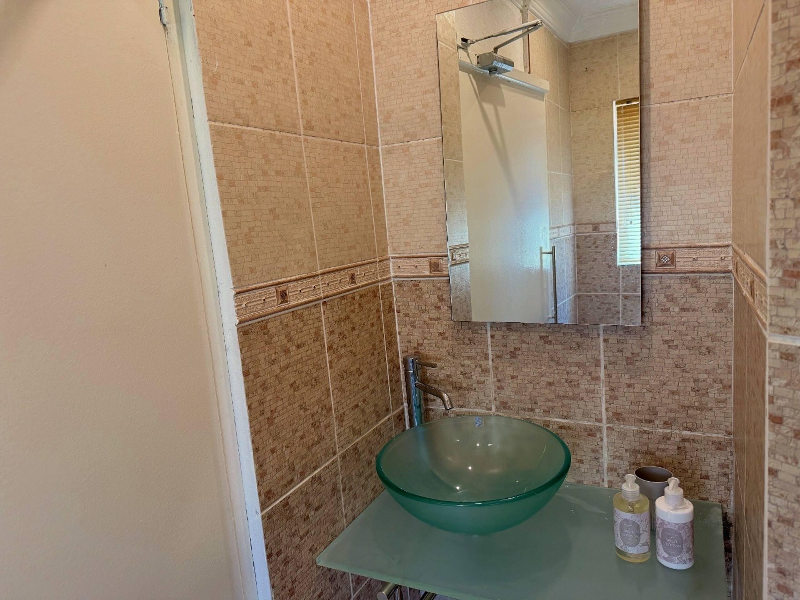 Bathroom with glass vessel basin and mirrored cabinet