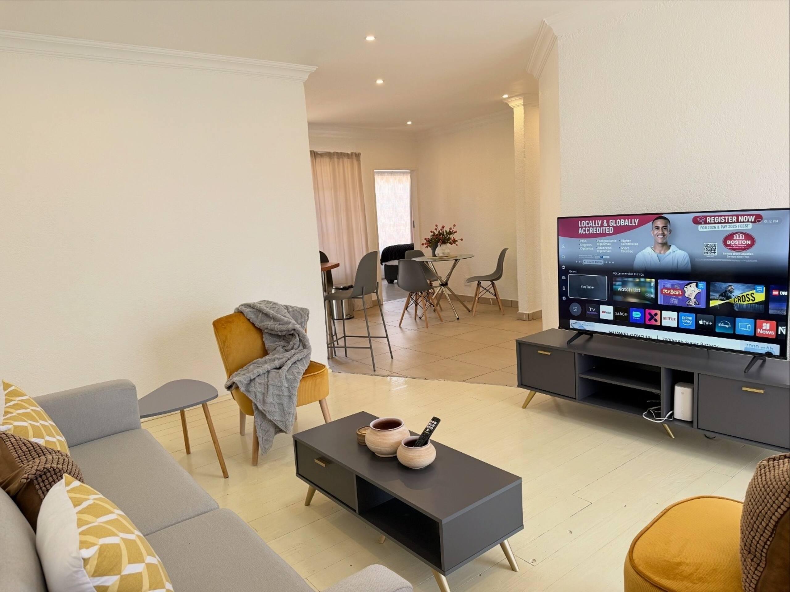 Living room with mounted smart TV, opening onto the dining area