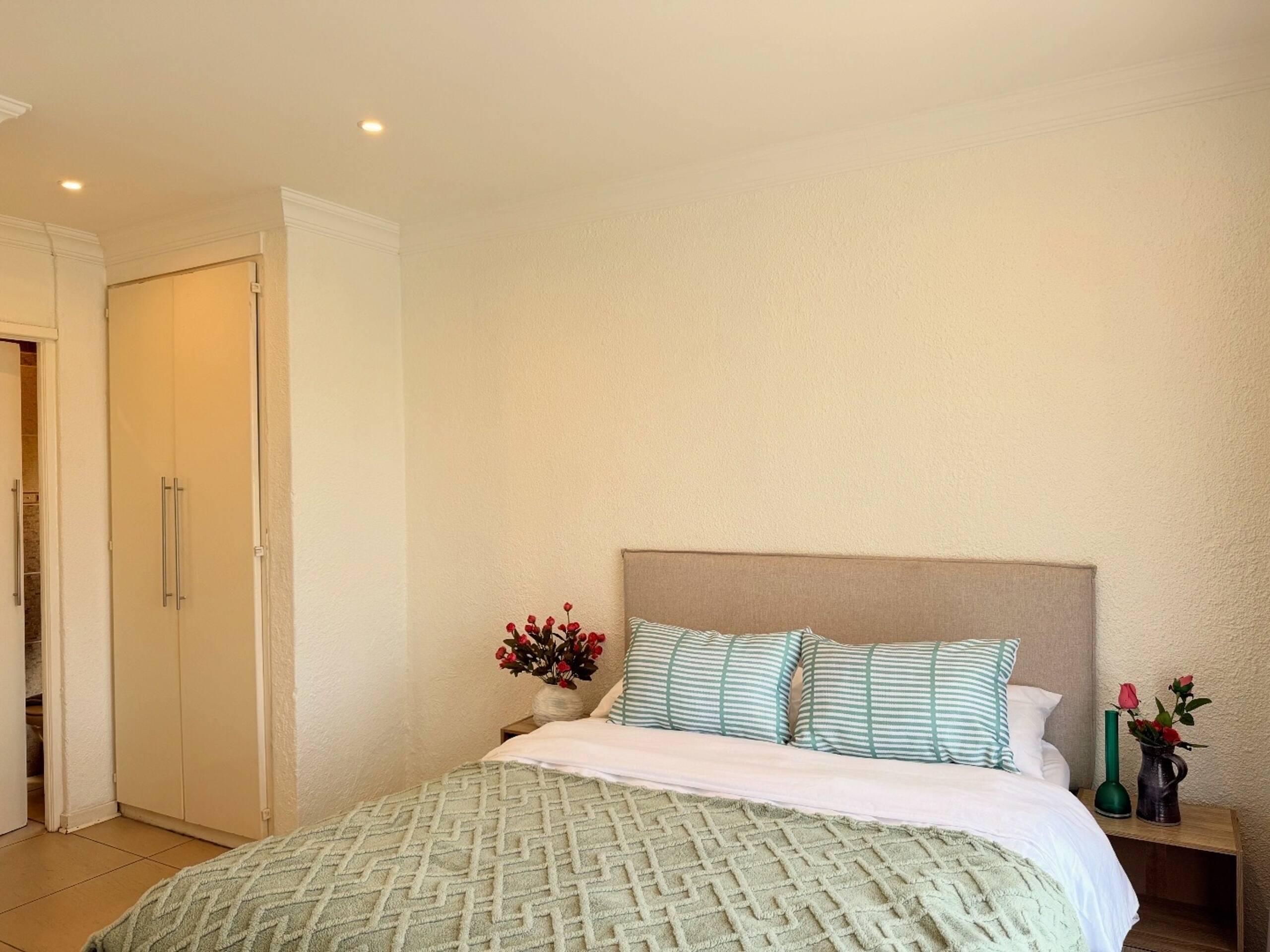 Bedroom with sage-striped pillows and built-in wardrobe